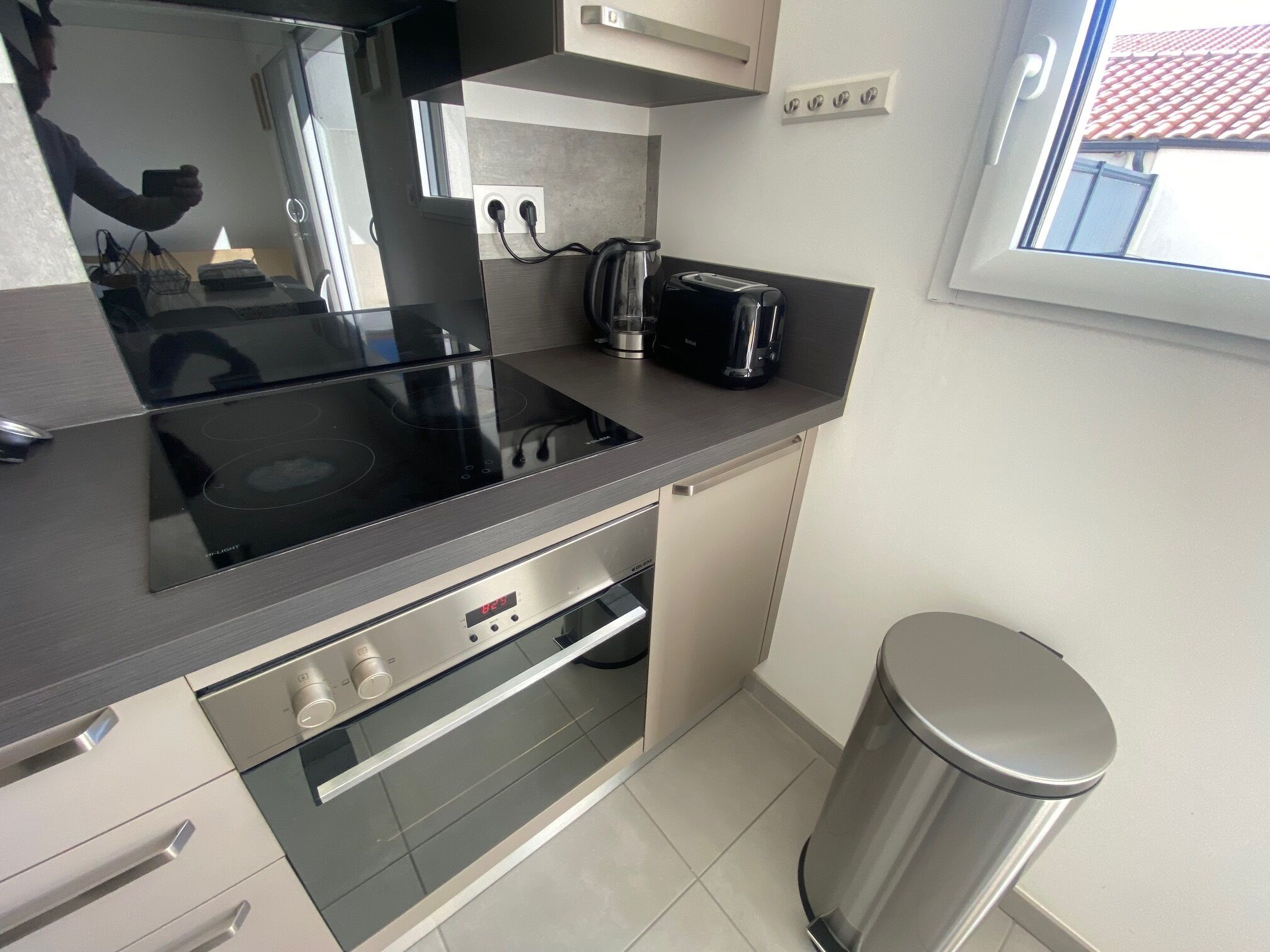 A modern kitchen with a built-in stove, a coffee maker, and a trash can.