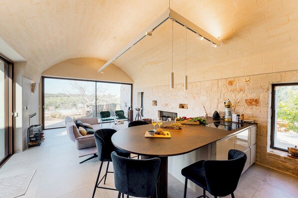 Una cocina amplia con una isla grande, sillas modernas y una chimenea.