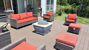Una terrazza con mobili in vimini e un tavolo da fuoco in pietra.