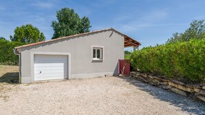 A single-story building with a garage, a small window, and a gravel driveway. - Holiday Home 'Les Cinsault' with Private Pool, Wi-Fi and Air Conditioning (Vaison-la-Romaine)