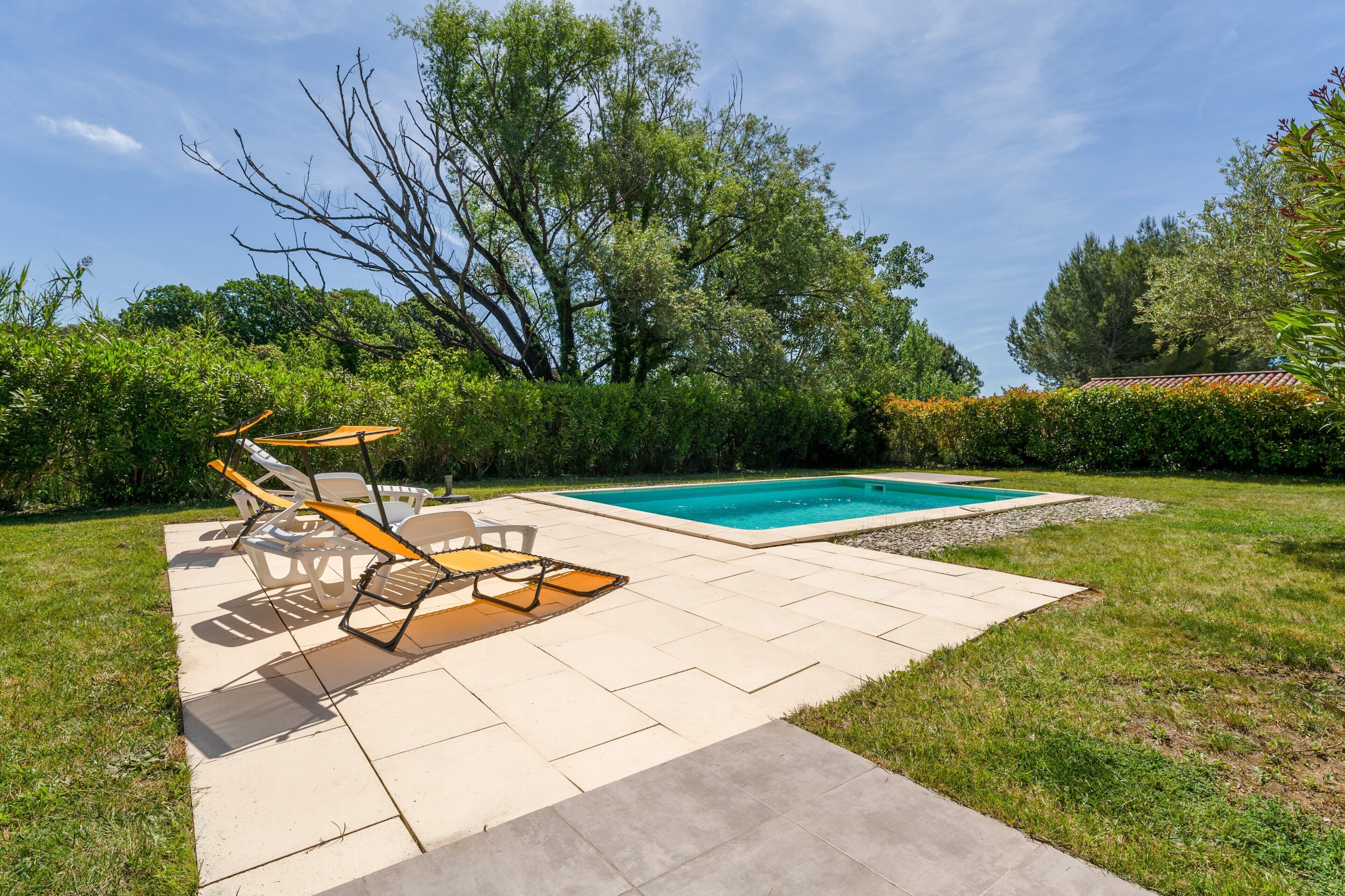 A backyard with a swimming pool, patio furniture, and a lawn.