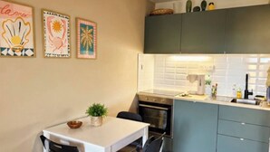 Une cuisine compacte avec une table et des chaises blanches, une petite plante en pot et un four à micro-ondes.