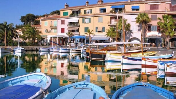 Un port de plaisance avec des bateaux amarrés, des bâtiments dotés de balcons et des palmiers.