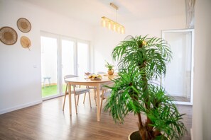 A dining area with a table, chairs, a hanging light fixture, and a potted plant. - Luxury Designer Family Retreat with Serene Nature Views - Steps from the Beach (Setúbal)