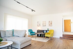 A modern living room with a sofa, two chairs, a small table, and artwork on the wall. - Luxury Designer Family Retreat with Serene Nature Views - Steps from the Beach (Setúbal)