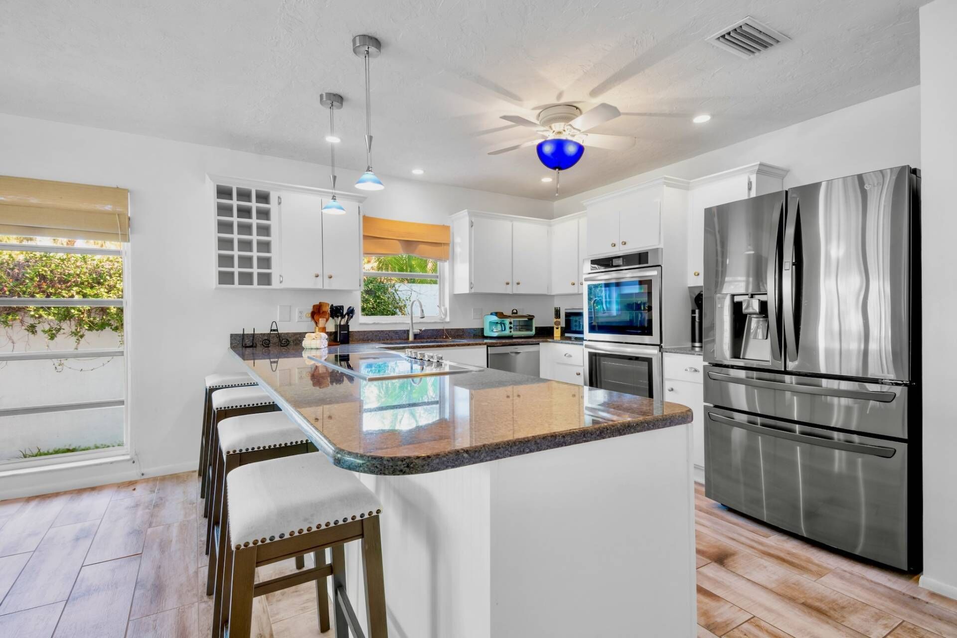 A modern kitchen with a central island, stainless steel appliances, and a ceiling fan.