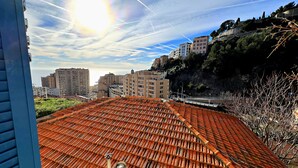 Un tetto con tegole tradizionali, cielo sereno con scie di condensazione e edifici sullo sfondo.
