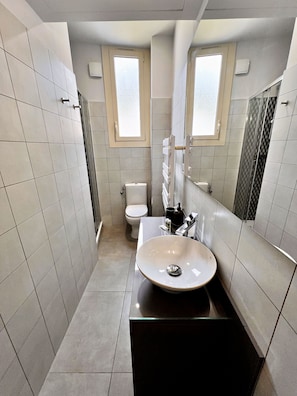 A modern bathroom with a large sink, toilet, and shower. - Appartement 1B - MyResidenced'Azur (Beausoleil)
