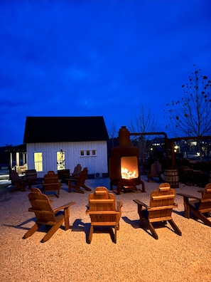 Un espace extérieur accueillant, aménagé avec des chaises en bois et un poêle à bois.