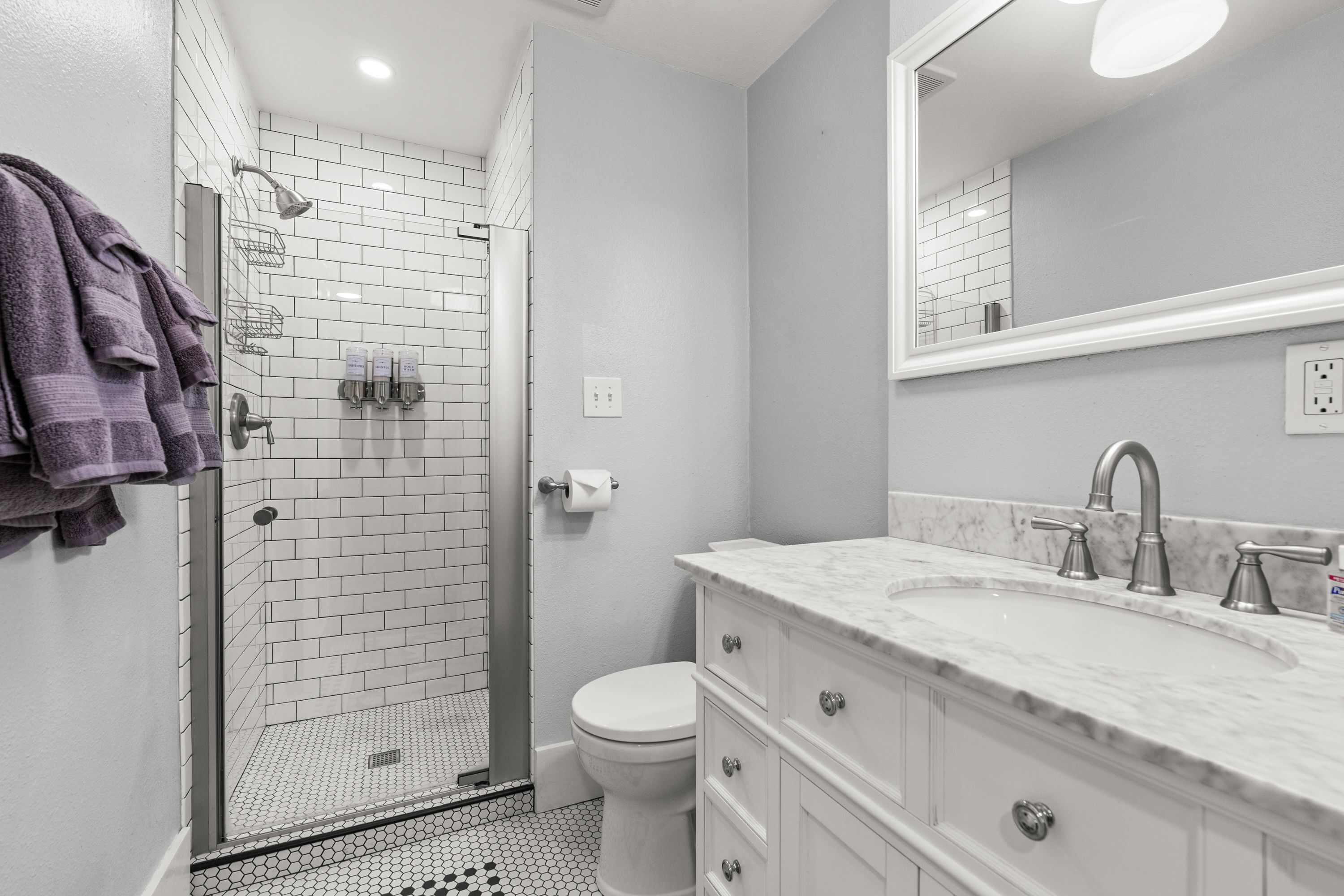 A modern bathroom with a glass-enclosed shower, a white toilet, and a marble sink.