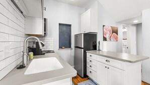 Une cuisine moderne avec des meubles blancs, un réfrigérateur en acier inoxydable et un évier.