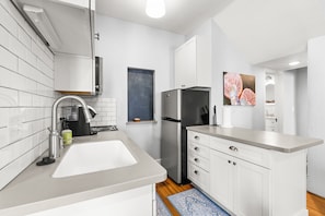 A modern kitchen with white cabinets, a stainless steel refrigerator, and a sink.