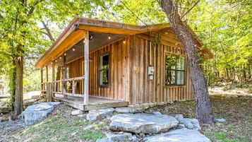 A wooden cabin with a porch, large windows, and a stone pathway.