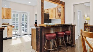 A kitchen with wooden cabinets, a bar area with stools, and a large mirror. - Spring Water Ranch (Red Lodge)