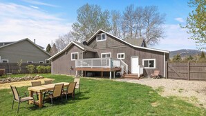 A two-story house with a deck, a covered patio, and a fenced backyard. - Spring Water Ranch (Red Lodge)