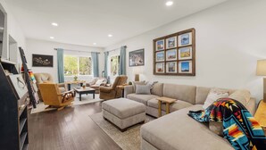 A living room with a sofa, ottoman, and chairs, a coffee table, and a wall with framed pictures. - Spring Water Ranch (Red Lodge)