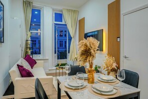 Ein Essbereich mit einem Tisch für vier Personen, einer Couch und einem Fenster mit Vorhängen.