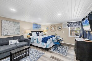 Ein Schlafzimmer mit Bett, Sofa, kleinem Tisch und Stuhl.