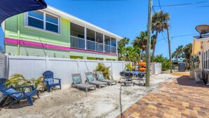 Une maison aux couleurs vives, dotée d’un patio couvert, d’un espace salon extérieur et d’un barbecue.