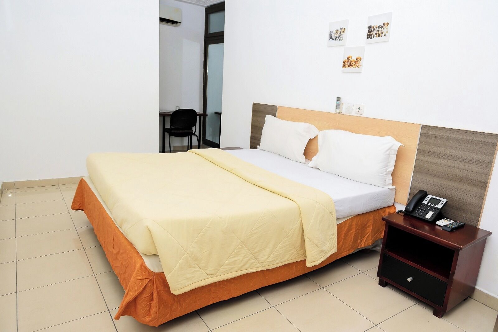 Une chambre d’hôtel avec un lit, une table de chevet avec un téléphone et une chaise dans un coin.