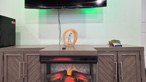 A fireplace with a TV mounted above it, a small plant, and a decorative wooden circle.