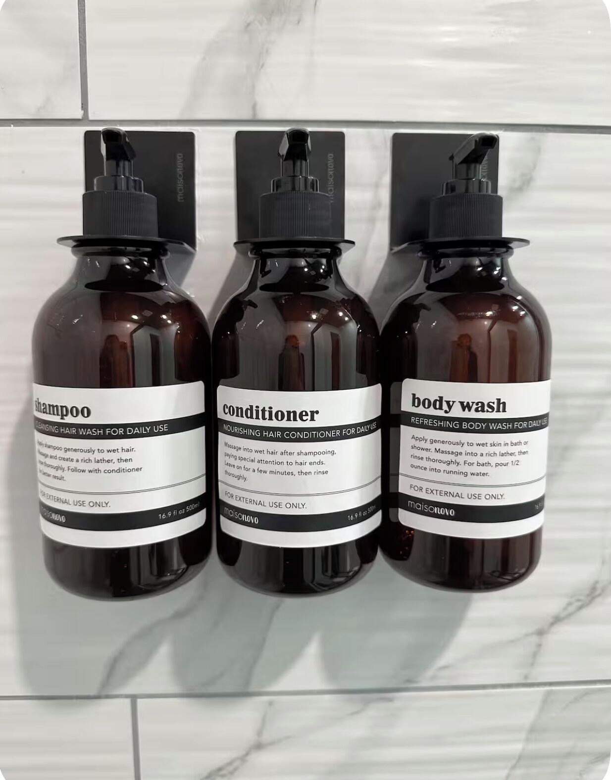 Tre flaconi di prodotti per la cura dei capelli su una superficie piastrellata.