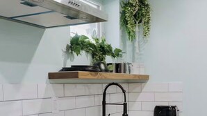 A kitchen with white cabinets, a black faucet, a wooden cutting board, and a toaster.