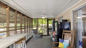 Um alpendre coberto com mesa e cadeiras, um ventilador de teto e vista para o exterior.