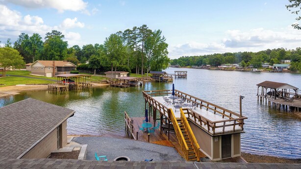 Uma propriedade à beira do lago com estruturas de cais, uma área de estar coberta e um edifício com telhado inclinado.