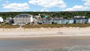 Ein Küstenhotel mit mehreren Gebäuden, einem Sandstrand und Blick aufs Meer.