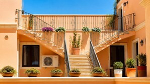 Un bâtiment doté d’un escalier central, de plantes en pot et d’une fenêtre avec un appareil de climatisation.