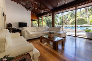 A spacious living room with a large sofa, a coffee table, and a television. - Casa Flamboyant - Granja Viana (Carapicuíba)
