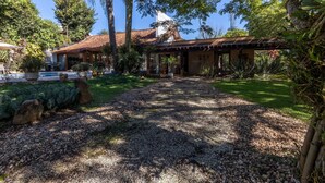 Una casa con porche techado, piscina y camino de grava.