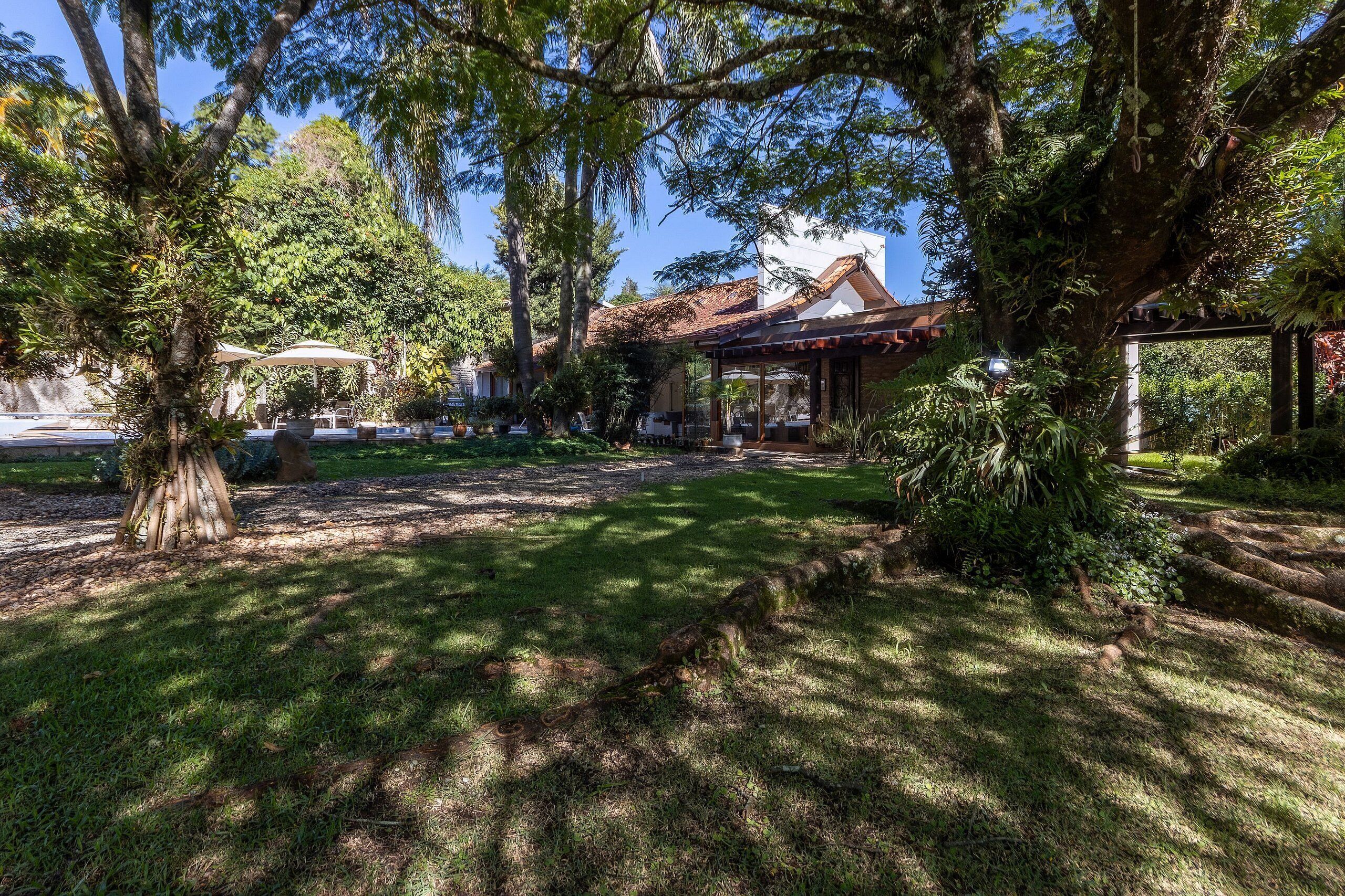 A garden with a gazebo, trees, and a building with a red roof.