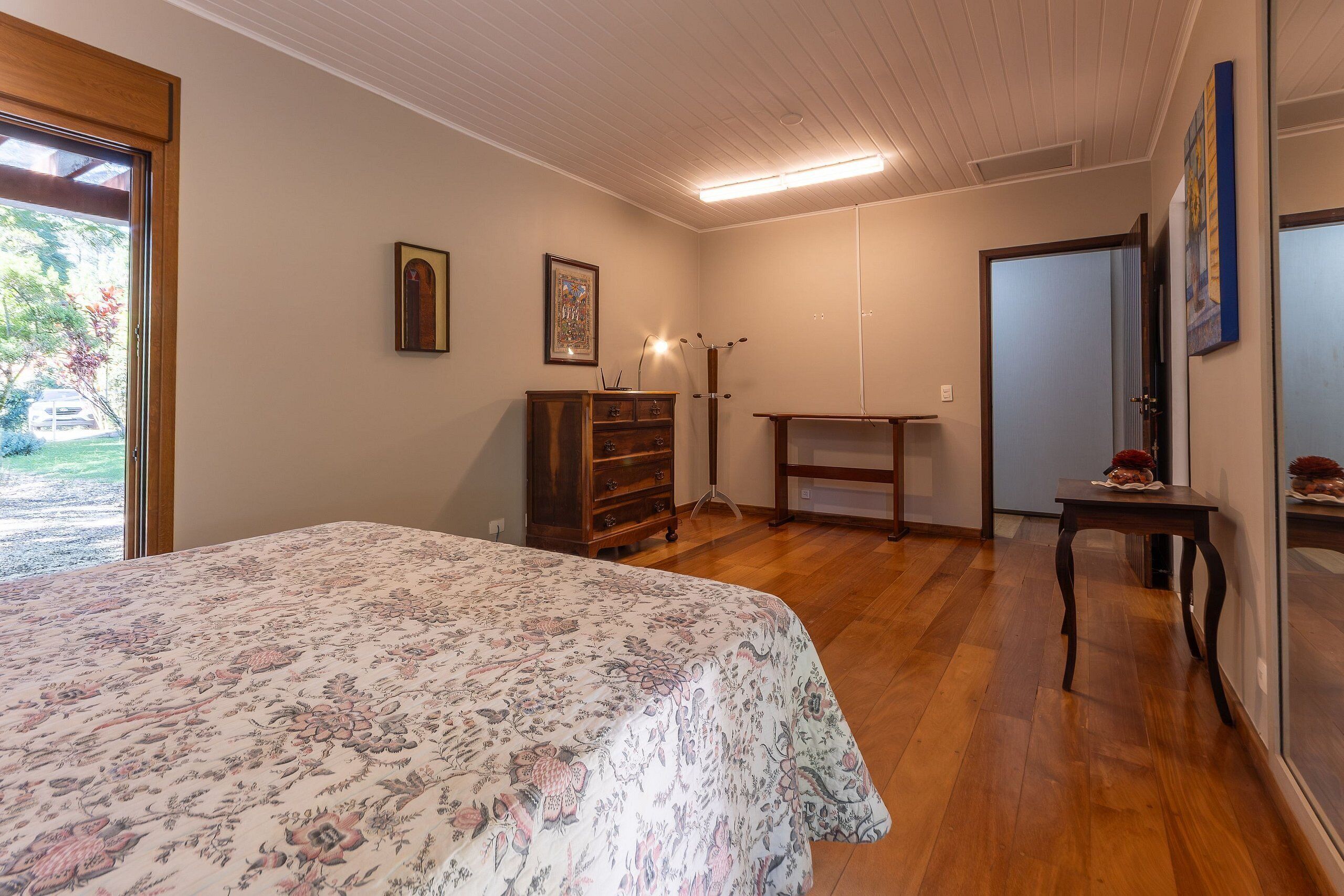 A bedroom with a bed, wooden dresser, and a desk.