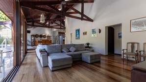Un salón comedor amplio con un sofá seccional grande, piso de madera y un techo alto con vigas a la vista.