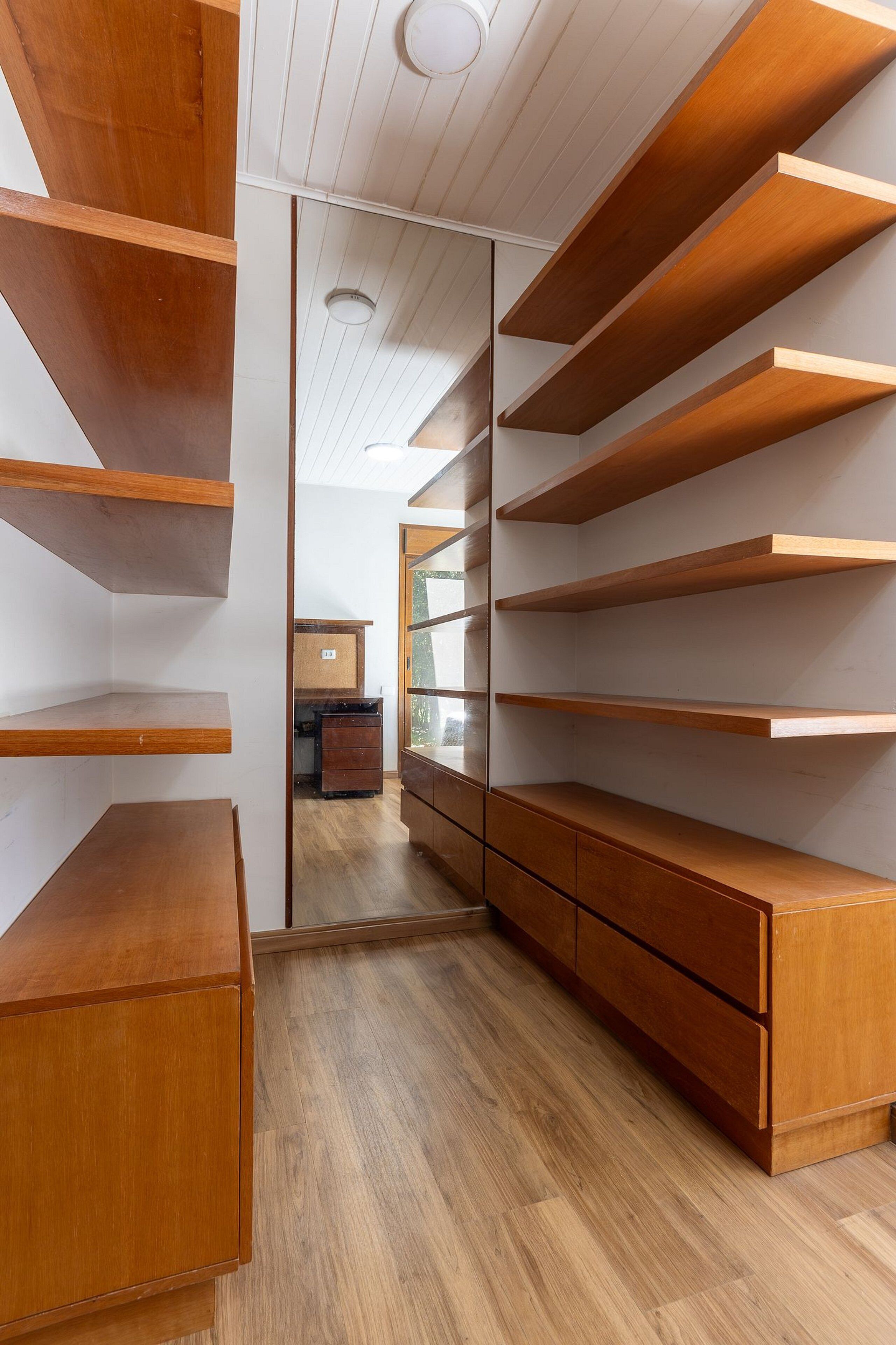 A modern interior with wooden shelves and cabinets, a wooden floor, and a view into another room.