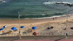 Een strand met parasols, een zandstrand en de oceaan.