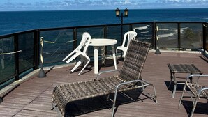 Een terras met rieten stoelen, een tafeltje en een lamp.