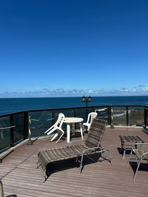 A deck with wicker chairs, a small table, and a lamp. - Sand, Sun and Sea - Apart-Service Ondina / Salvador (Salvador)