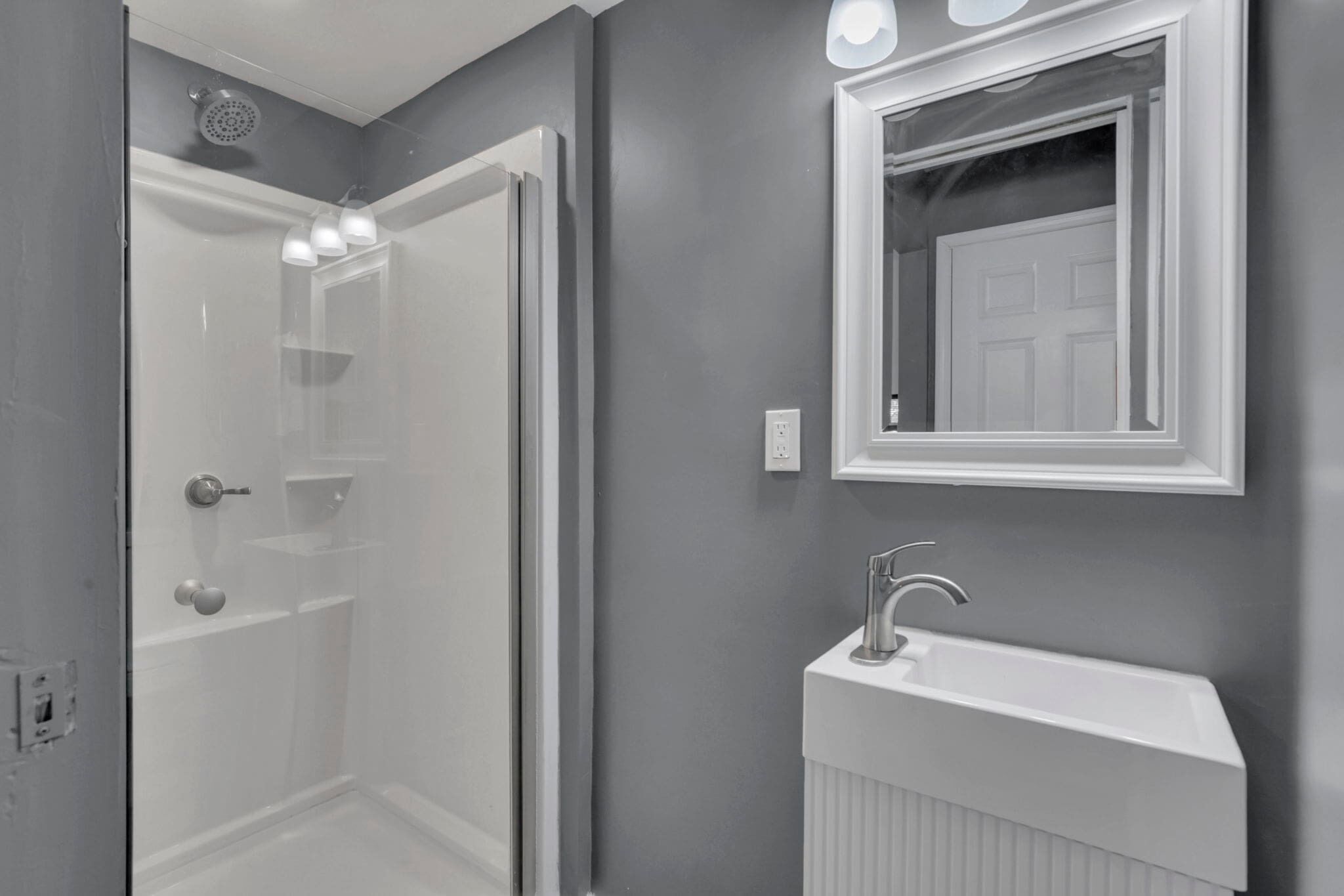 A bathroom with a shower, a sink, and a mirror.