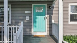 Una casa con puerta delantera color turquesa, un buzón y un cartel con el número 1114.