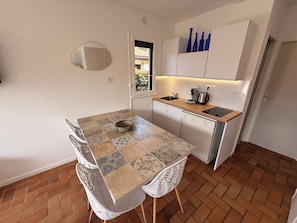Une cuisine compacte avec un carrelage au sol, une table à manger avec des chaises, un four encastré et une fenêtre donnant sur un beau paysage.