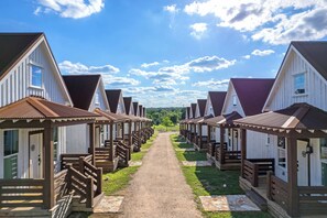 Une rangée de cabanes blanches aux toits bruns et aux balustrades en bois, reliées par un chemin de gravier.