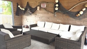 A wicker sofa set with white cushions, a wooden wall, and a notice sign. - Capn's Corner--1 BR, 1 Bath, Garage, Close to Beach, Dogs OK! (Port Aransas)
