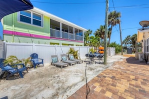 A colorful house with a covered patio, outdoor seating, and a barbecue grill.