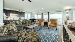 A spacious living area with a large sectional sofa, a ceiling fan, and a view of the ocean. - Direct Beach Access Classic Surfside Home (Surfside Beach)