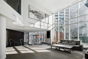Un hall d’entrée spacieux, doté d’une grande fenêtre, d’un canapé et d’un escalier.