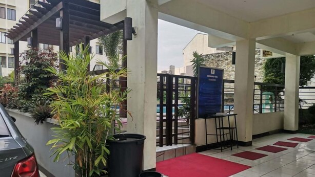 Un espace extérieur abrité comprenant une piscine, des plantes en pot et un panneau d’affichage.