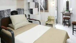 Une chambre à coucher comprenant un lit, un bureau, une chaise, un ventilateur et un escalier.
